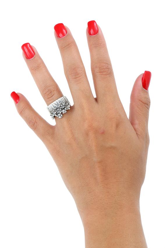 Modelo muestra en dedo anular izquierdo un anillo de plata 925 ancho con forma de florecitas de jardín. Joyería artesanal, anillo ajustable, hecho a mano.