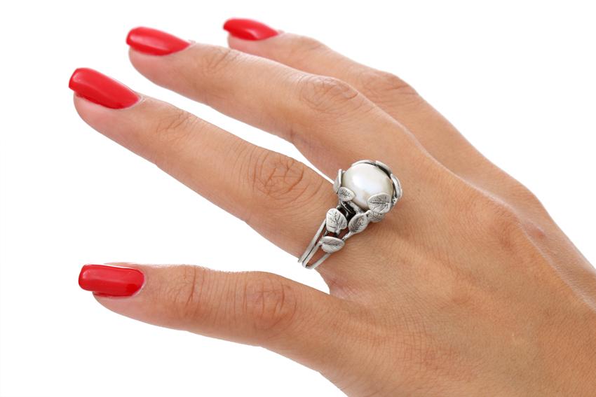 Chica muestra en anular derecho un anillo de plata con perla cultivada y hojitas