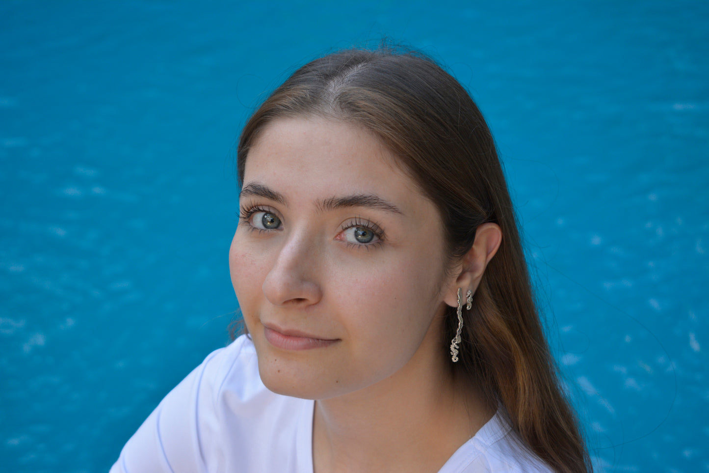 Modelo luce en su oreja izquierda un arete de plata con forma de alfa con caballito de mar y un arete simple de caballito de mar. Aretes en plata 925 elaborado con materiales sustentables, joyería mexico Eva Carrillo